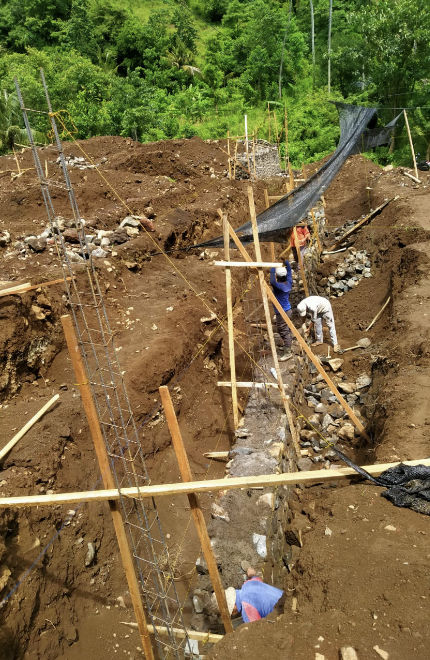 Construction workers digging water drainage channel in Amed, Bali