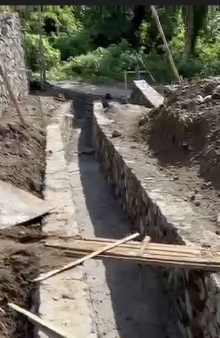 Water drainage gutter with river stone supporting walls