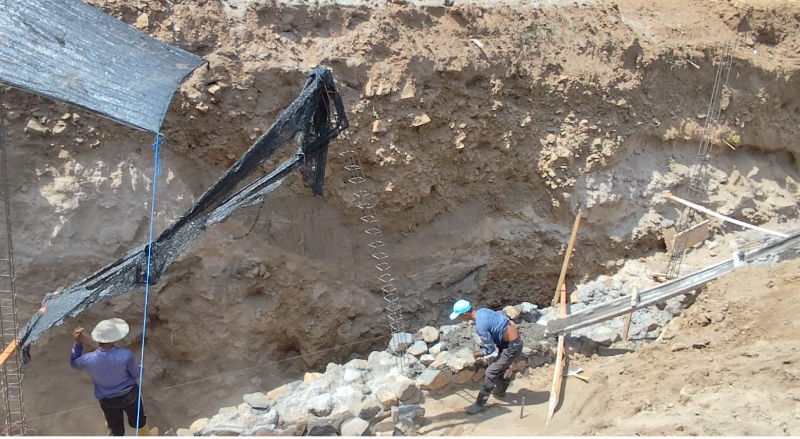 Construction workers digging foundations for retaiiing walls