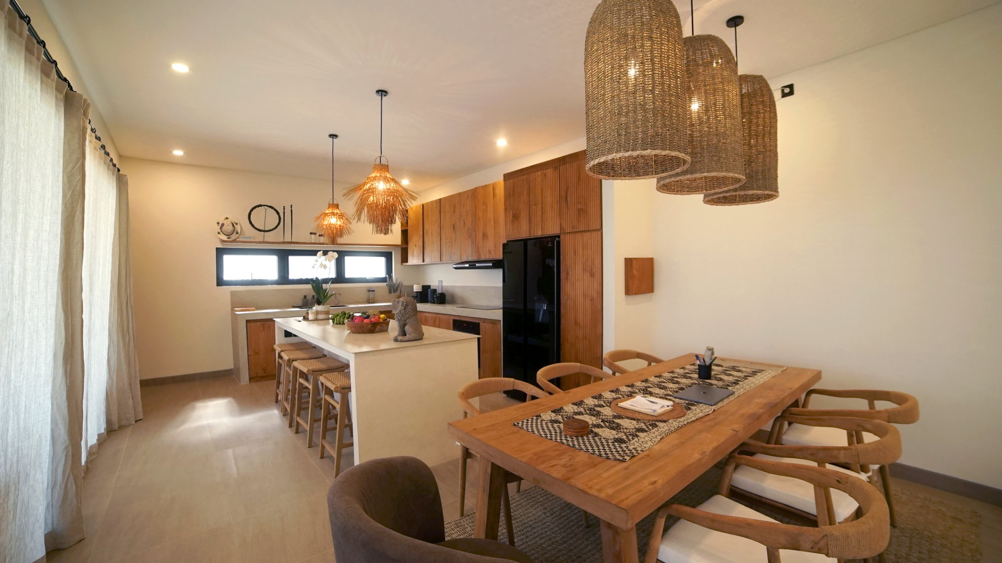 Dining table and kitchen in an open plan design of a luxury villa for sale in Amed.