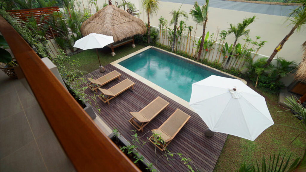 Birds eye view of a swimming pool in Amed with wooden sunbeds.