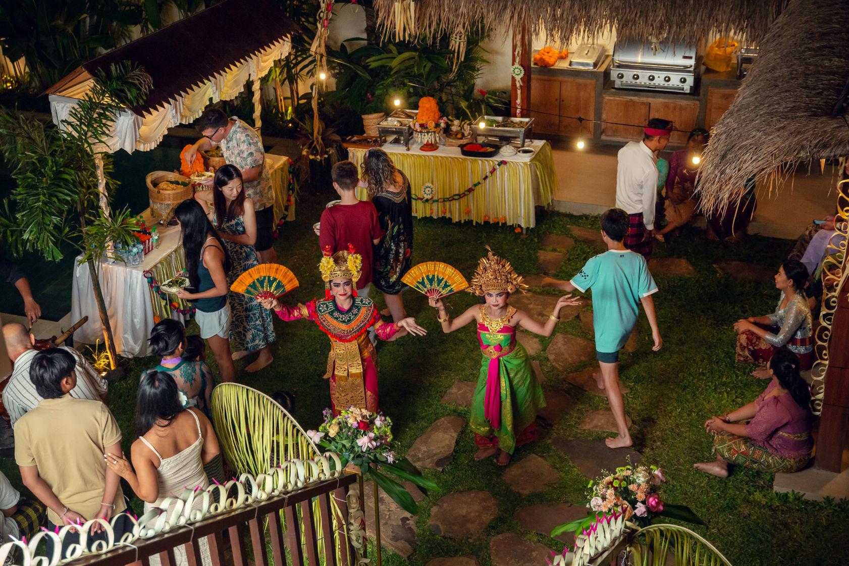 Balinese Cultural Dinner Balinese cultural dinner at the Vesica Villas Resort. Balinese dancers with people selecting food from the buffet. The villa is decorated in traditional Balinese style.