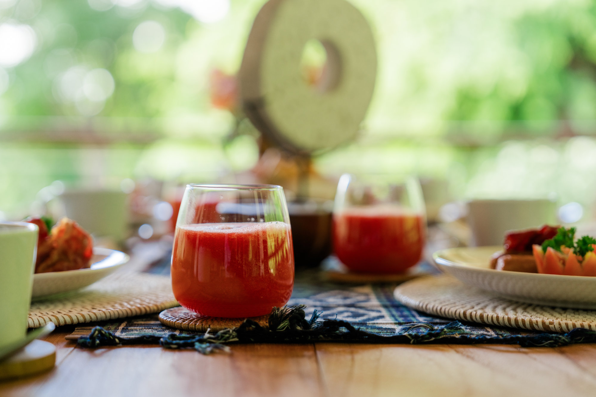 Dining Breakfast Close up of two glasses with red juice laid on a wooden table set for breakfast at the Vesica Villas Resort in Amed Bali