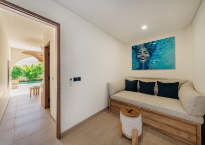 Daybed lounge looking through an open doorway toward patio greenery and pool at Angin Laut at Vesica Villas Resort in Amed