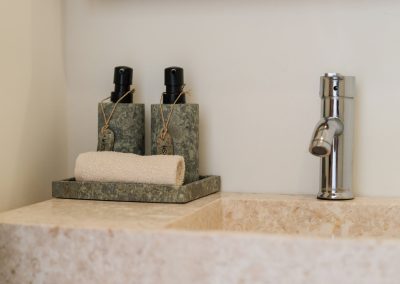Stone vessel sink corner with chrome faucet and speckled stone soap dispensers on a tray at Angin Laut at Vesica Villas Resort in Amed