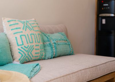 Close-up of teal and cream geometric throw pillows with cowrie-shell trim on a beige sofa at Angin Laut at Vesica Villas Resort in Amed