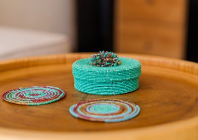 Turquoise beaded coasters and a beaded box on a round wooden tray at Angin Laut at Vesica Villas Resort in Amed