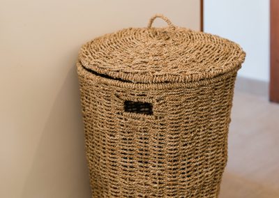 Tall cylindrical woven basket with lid standing on a light tiled floor at Angin Laut at Vesica Villas Resort in Amed
