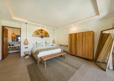 King bedroom at Angin Laut at Vesica Villas Resort in Amed, with sage accents, rattan pendants, fan wall art, slatted wardrobe, and full-length wood mirror