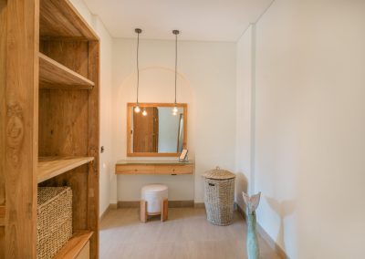 Vanity nook at Angin Laut at Vesica Villas Resort in Amed, with a floating wooden desk, square mirror, pendant bulbs, wicker hamper, and a small fish-tail sculpture