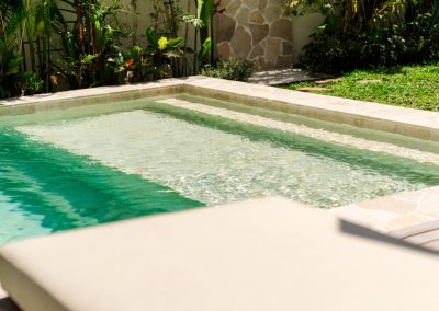 Corner of the private pool with submerged stone steps and lounger cushions at Villa Svara in Amed.