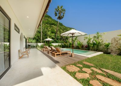 Pool garden with lawn stepping stones, outdoor shower, and marble terrace seating at Villa Svara in Amed.