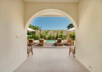 Arched doorway at Villa Svara framing the marble terrace, pool deck, and sun loungers at Vesica Villas Resort in Amed.