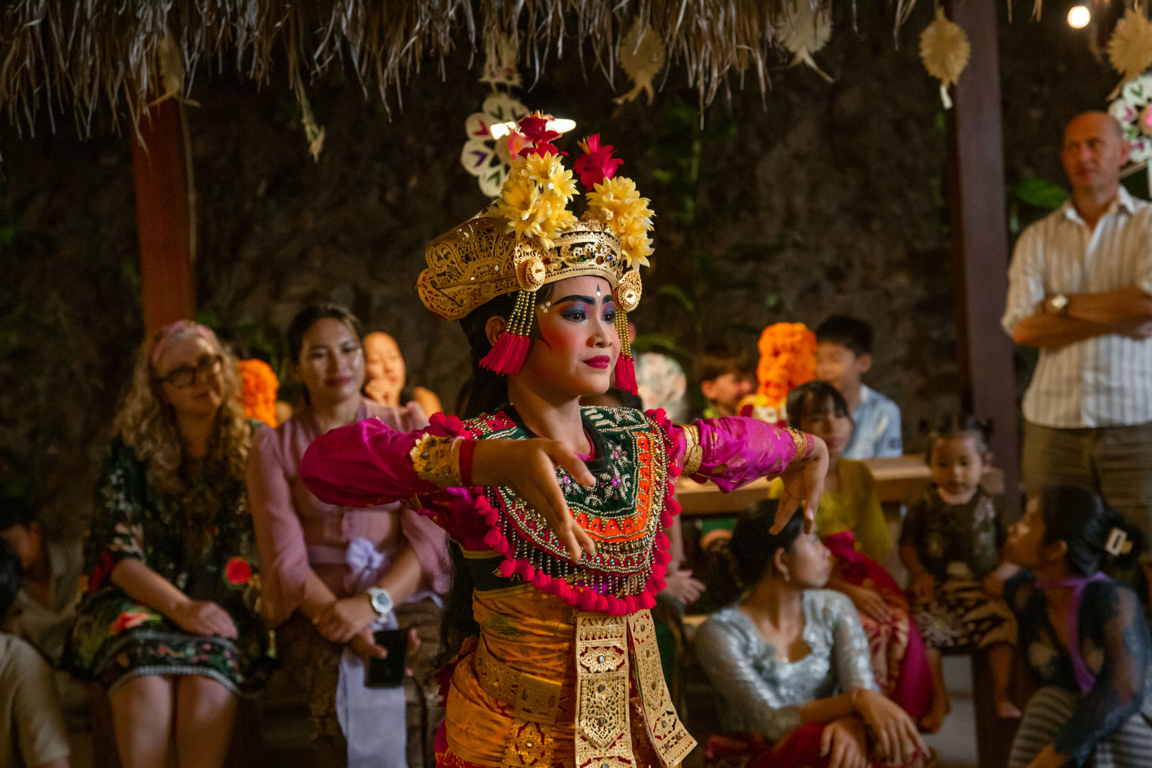 BaliCulturalDinner_020 Two Balinese dancers in gold headdresses and silk costumes performing on the lawn of a private villa at Vesica Villas Resort in Amed, with a traditional Balinese dinner set out beside the pool.